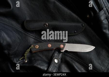 Survival, bushcraft knife with sheath in a black leather background Stock Photo