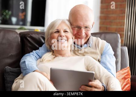 Senior couple browsing the internet together. Retirees using a tablet at home Stock Photo