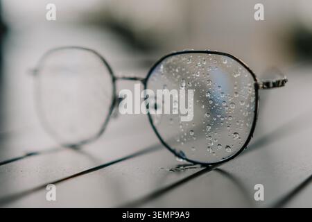 Eyeglasses water droplets rain falling on glasses on a table during a moody day Stock Photo