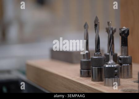 Professional CNC router bits and woodworking cutting tools arranged on a workbench in a furniture manufacturing workshop. Precision cutting equipment Stock Photo