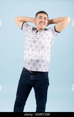 Young man holding hands behind head yawning or stretching relaxedly Stock Photo