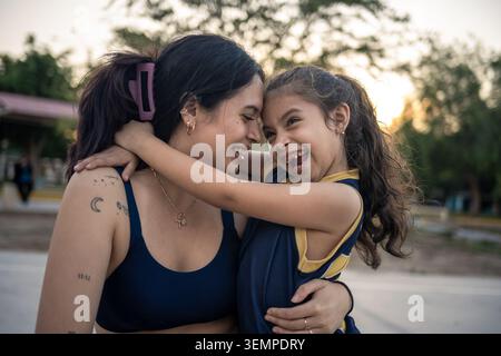 Laughing mother and daughter embracing outdoors Stock Photo