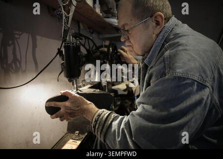 Senior craftsman mending a shoe in his workshop Stock Photo