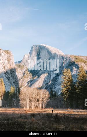 Two people walking in a meadow below Half Dome mountain Stock Photo