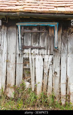 detail of doors and window with rusty hinges on old derelict abandoned wooden stable with attractively split, knotted and grainy old weathered wood Stock Photo