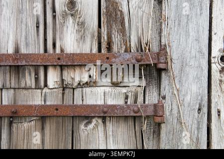 detail of doors and window with rusty hinges on old derelict abandoned wooden stable with attractively split, knotted and grainy old weathered wood Stock Photo