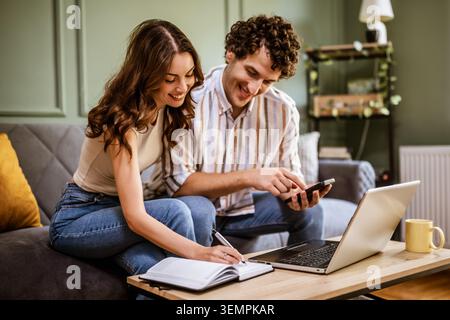 Couple discussing home finances while examining bills. They are checking financial documents and calculating family budget in living room. Stock Photo