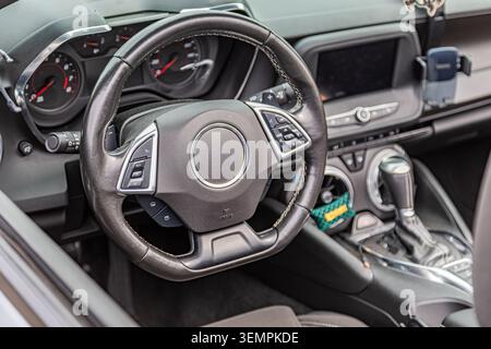 Premium steering wheel with textured leather finish showcasing multi-function buttons, airbag safety feature, and sleek modern dashboard including cir Stock Photo