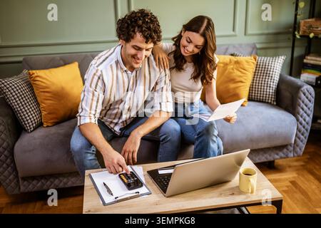 Young couple calculating home finances while checking bills. Stock Photo