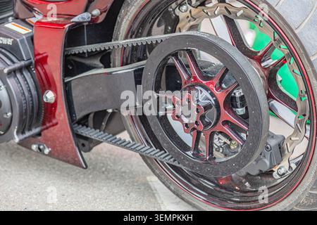 Sporty high-performance motorcycle rear wheel detail, featuring multi-spoke dark rim with red accents, star-shaped hub, textured tread tire, multi-slo Stock Photo