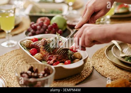 Close Up of Carving Roasted Meat at Festively Set Dining Table Stock Photo