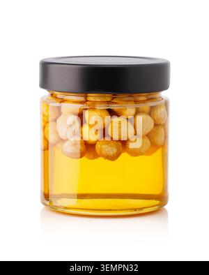 Hazelnuts preserving in golden honey standing inside a glass jar with a black lid Stock Photo