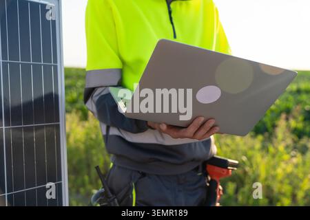 Engineer with laptop next to solar panel. Stock Photo
