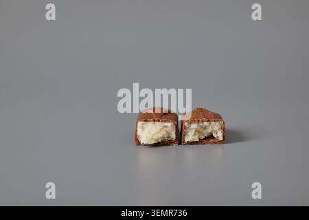 Two halves of a chocolate bar with coconut filling on a gray background Stock Photo