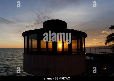 Sunset mirror. The sun's rays break through the glass building. The sun is setting in the sea. Stock Photo