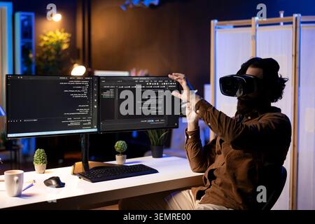 Programmer using high-tech VR headset to secure company servers from virus attacks, with IT remote employee building firewalls protecting data using futuristic virtual reality technology. Stock Photo