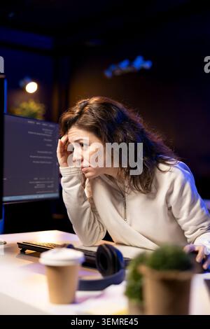 Tired software developer hurting from too much stress accumulated while doing quality assurance, computer scientist suffers from headache after inspecting coding on PC for too long. Stock Photo