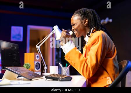 Happy developer at laptop programming, exuberating after writing lines of code, using development tools, ecstatic woman in home office pleased after finishing debugging software on notebook. Stock Photo