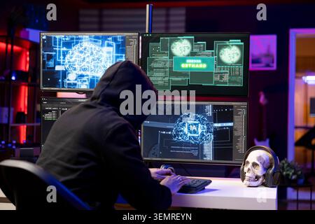 Hooded hacker typing on PC keyboard, using AI to break into secure computer systems and bypass security, rogue engineer uses neural networks to attack weak spots in company networks. Stock Photo