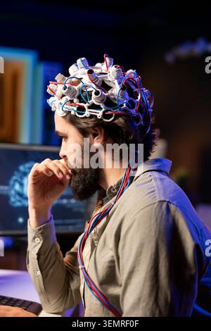 IT admin coding and using EEG headset to upload brain into computer, gaining immortality, neuroscientist engineering transhumanism experiment, inserting consciousness into cyberspace. Stock Photo