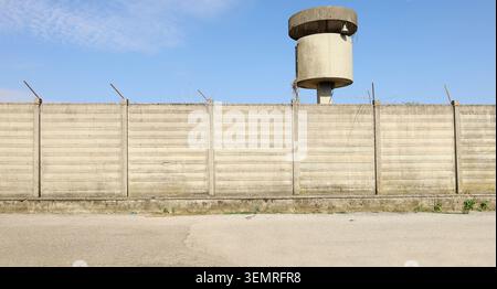 Concrete precast compound wall with cement watchtower on behind. Road in front. Background for copy space Stock Photo