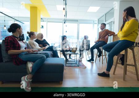 Low angle perspective of a multiethnic team of business colleagues sitting in a modern open-plan workspace, collaborating on projects using digital ta Stock Photo