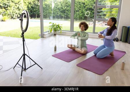 African American women coach-student in sportswear at home doing yoga on purple mats, copy space Stock Photo