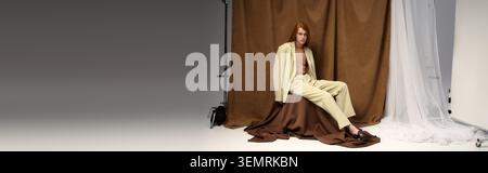 A handsome young man with flowing red hair poses elegantly in stylish attire. Stock Photo