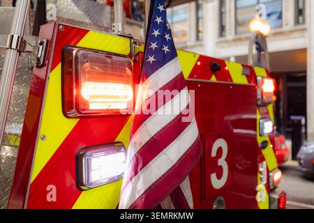 Close-up of United States of America flag on flashing fire truck on city street. Emergency services, patriotism, first responders and public safety co Stock Photo