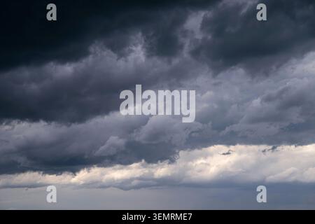 A dramatic cloudscape featuring dark rain clouds and patches of light where the sunlight breaks through on a changeable day. A meteorological backdrop Stock Photo