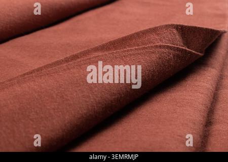 Close-up of brown cotton fabric with elegant folds and visible woven texture, showcasing natural textile material used in garment production. Stock Photo