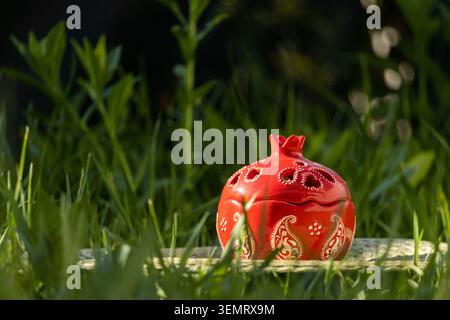 Ceramic Red Pomegranate-Shaped Bowl with Lid on Green Grass Stock Photo