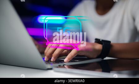 Close up hand typing on laptop keyboard with 5G technology hologram icon on screen background. Fast internet connection network concept for business o Stock Photo