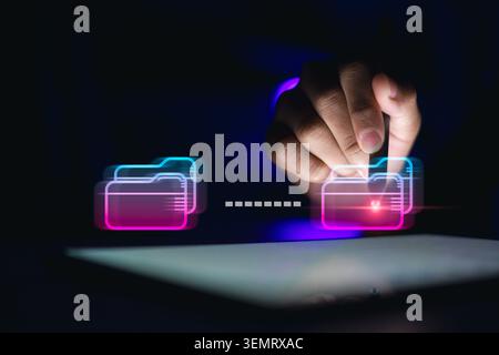 Professional using stylus on tablet with glowing neon digital folders transferring data. Futuristic document management system, cloud storage, file sh Stock Photo