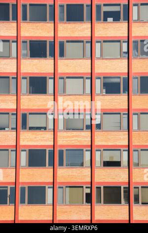 Red brick building facade with repetitive windows and red vertical columns in Madrid, Spain. Stock Photo