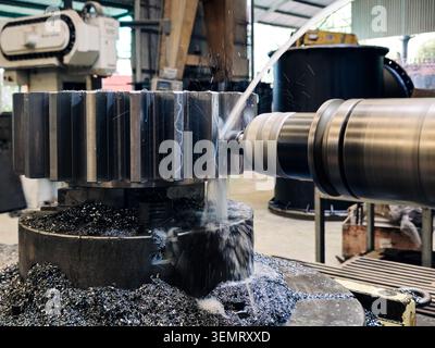 Precision CNC Machining of Heavy Duty Steel Gear in Factory. A heavy-duty steel gear being precisely milled and shaped by a CNC machining center in a Stock Photo