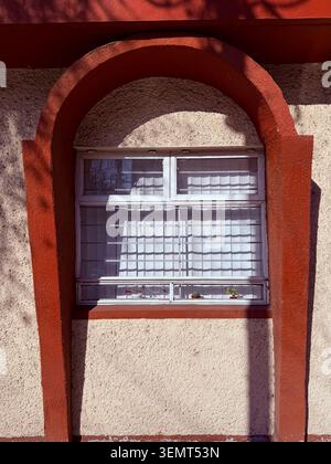 Arched window with metal bars and strong tree shadows on a residential facade in Roma Sur, Mexico City, Mexico. Stock Photo