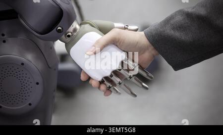 AI Robot shaking hands with man. Close up of human shaking hand with robotic arm. Symbolizing collaborate between people and artificial intelligence o Stock Photo