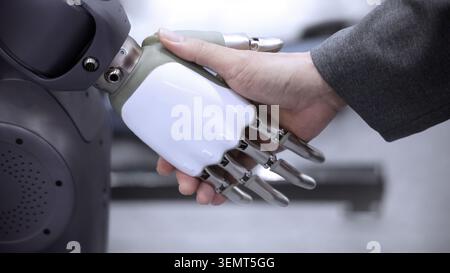 AI Robot shaking hands with man. Close up of human shaking hand with robotic arm. Symbolizing collaborate between people and artificial intelligence o Stock Photo