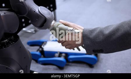 AI Robot shaking hands with man. Close up of human shaking hand with robotic arm. Symbolizing collaborate between people and artificial intelligence o Stock Photo