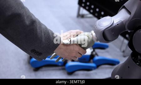 AI Robot shaking hands with man. Close up of human shaking hand with robotic arm. Symbolizing collaborate between people and artificial intelligence o Stock Photo