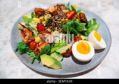 Fresh quinoa salad with grilled chicken, strawberries, avocado, hard-boiled egg, and mixed greens Stock Photo