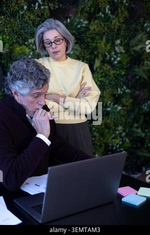 Senior male and female colleagues collaborating, discussing strategies, and analyzing data in an office environment Stock Photo