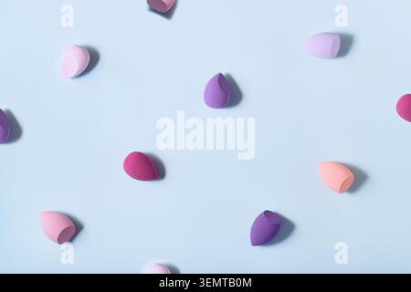 Colorful makeup sponges creating pattern on blue background Stock Photo