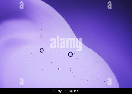 Serum with bubbles on purple background, close-up Stock Photo