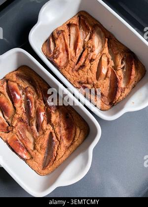 Two dishes of gluten-free apple pie sit on a dark kitchen counter. The pies are warm and fresh, ready to be served for dessert after a family gatherin Stock Photo
