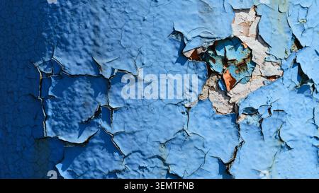 Close-up of cracked and peeling light blue paint on an old metal pipe, revealing layers of rust and previous coatings. Stock Photo