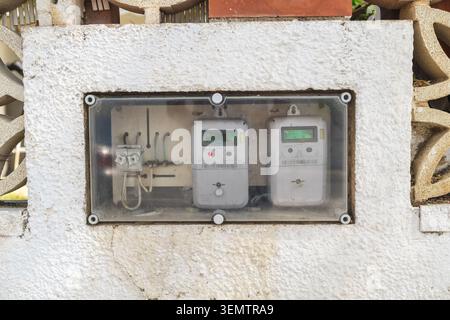 Digital electricity meters installed inside protective outdoor utility enclosure on residential property wall, smart energy monitoring equipment Stock Photo