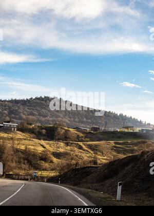 low mountains and M6 highway illuminated by the setting sun in Lori Province of Armenia on sunny spring evening Stock Photo