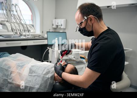 Male dentist using intraoral scanner on patient in modern office Stock Photo